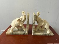 Front view of the pair of carved alabaster elephant bookends, showing symmetrical design and textured elephant figures on veined alabaster base.