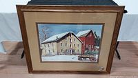 Full view of framed print showing winter rural scene in brown wooden frame with tan textured mat.
