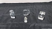 Four clear crystal items arranged on black fabric: a Baccarat clear owl figurine, a Baccarat clear elephant figurine, a Lalique owl paperweight with frosted details, and a Lalique hawk bird paperweight with frosted engraving.