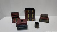 Full view of the complete set of six book-themed wooden and ceramic office decor items including tissue box, pen holder, bookends, and small boxes.