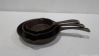 Three cast iron skillets nested inside each other, showing overall condition and size difference
