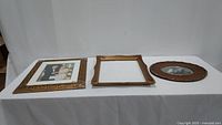 Three wooden gold tone frames laid on a white table, showing sizes and styles