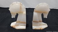 Front view of both onyx horse head bookends placed side by side on a black backdrop, showing the detailed carved horse heads and natural stone veining.