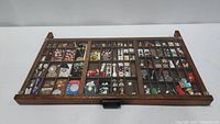 Top view of full wooden printer's tray showing multiple compartments filled with vintage collectibles.