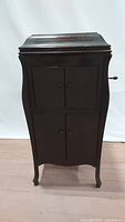 Front view of the dark wood phonograph cabinet with curved sides and four doors.