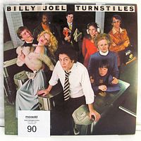 Front cover of the Billy Joel Turnstiles vinyl album showing the group photo on subway turnstiles with title at top.