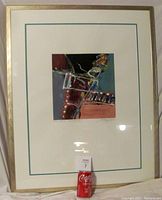 Full framed painting with white mat and teal inner line, displayed with soda can for scale.