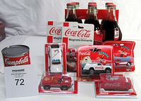 Photo showing entire lot including six pack of unopened Coke bottles in red cardboard carrier, five die cast Coca Cola vehicles in original packaging, and two sealed Coca Cola magnets