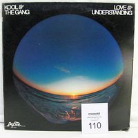 Front cover of Kool And The Gang 'Love & Understanding' vinyl LP showing fisheye ocean sunset artwork and De-Lite Records logo.