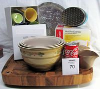 Photo showing the full lot with ceramic nesting bowls, Sunbeam Hotpot box, eight coffee mugs, silver serving tray, cream and sugar set, cheese grater, and butcher block board.