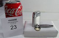 Two vintage lighters side by side next to a Coca-Cola can for size reference, one rectangular Ronson Typhoon and one bullet shaped lighter.