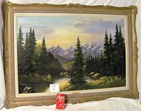Full view of the original oil painting by Rose Schul showing the entire framed artwork with landscape scene including trees, river and mountains with a Coke can for size reference.