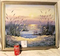 Framed oil painting of a seascape with sunset, reeds, boat, and chair. Includes reference item (Coca-Cola can) for size scale.