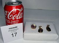 Photo showing size comparison with a Coca-Cola can and the three-piece ring and earrings set displayed on a white pad.