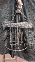 Front view of the 3 light chandelier showing circular frame, candle-style bulb holders, and distressed finish.