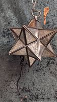 Star-shaped mercury glass pendant light hanging with electrical cord and chain visible
