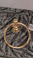 Front view showing circular polished brass towel ring and decorative mounting base.
