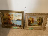 Two framed oil paintings by Helen Muddiman showing autumn Muskoka landscapes side by side on floor.