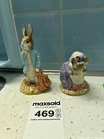 Front view showing Peter Rabbit holding a red pocket handkerchief and Lady Mouse curtsying in purple dress