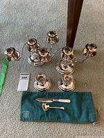 All items together including five silver plate candle holders, serving ladle and spreader on carpet.