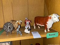 Shelf with multiple animal figurines and farmer, including Beswick bull cow, sheep, and pewter farmer with wheelbarrow.