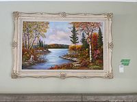 Frontal view of the framed painting showing the colorful fall river landscape and ornate frame
