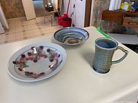 Wide view showing all three items: the Wade mug, large painted floral bowl, and blue swirl pottery bowl.