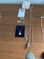 Full lot overview showing pair of earrings, three necklaces with pendants including the Dutch shoe charm, and one pendant on a card.