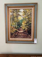 Full view of framed oil painting showing country road and fall foliage.