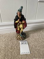 Front view of the Royal Doulton Pied Piper figurine standing on a carpeted floor with lot number card.