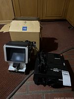 Elmo Editor 912 slide editor with box and Vivitar projector placed side by side.