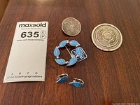 Full lot photograph showing one blue leaf shaped pin, matching pair of blue leaf clip-on earrings, and two round Aztec calendar motif pins all in sterling silver on wood surface with auction card.