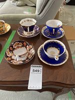 Overhead view of all four teacup and saucer sets arranged on wood table