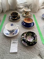 Overview of all five teacup and saucer pairs arranged on carpet