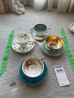 All four teacup and saucer sets arranged on carpet