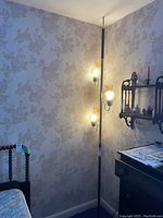 Full view of the floor to ceiling pole lamp placed in a corner wall with three amber glass shades lit up.