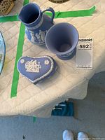 Photo showing Wedgwood blue jasperware jug, cup, and heart-shaped box placed on quilted surface.
