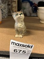 Front three-quarter view of small ceramic cat figurine showing detailed face and front.