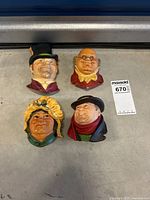 Four Bossons mini hanging wall figures laid on floor showing caricatured faces and color details.