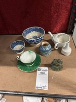 Lot showing green teacup and saucer, two blue patterned bowls, white teapot, blue jar, and green elephant figurine on table.