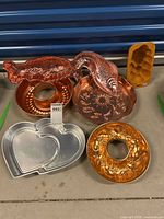 Overview of six assorted decorative food moulds on table including fish shapes, heart shape and circular moulds