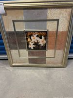 Full view of the framed art showing the gold frame with the central square floral painting.