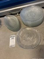 Set of glass lunch plates including stacked oval plates with leaf pattern and stacked round plates with textured radial pattern.