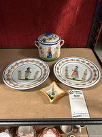 Full set showing two plates, lidded jar, and small box on shelf with red background