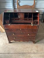 Full front view of antique wooden secretary desk showing multiple drawers and compartments, missing drop-down desk surface, missing knobs, and visible wear and damage