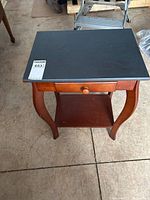 Top view of the wood side table showing the painted black top, curved legs, and a single drawer below the tabletop.