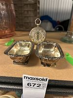 Photo showing two small silver-plated bowls and a small vintage alarm clock in the background.