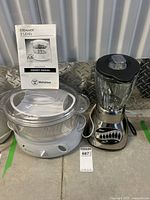 Photo showing Westinghouse two level steamer, Oster blender, and Westinghouse steamer owner's manual on concrete floor.