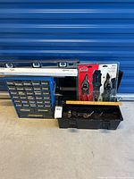Full view of tool storage lot including toolbox, hardware organizer, spirit level, and tin snips set