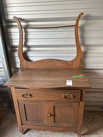 Front view of wooden washing stand cabinet showing drawer, cupboard doors, towel rack supports, and casters.